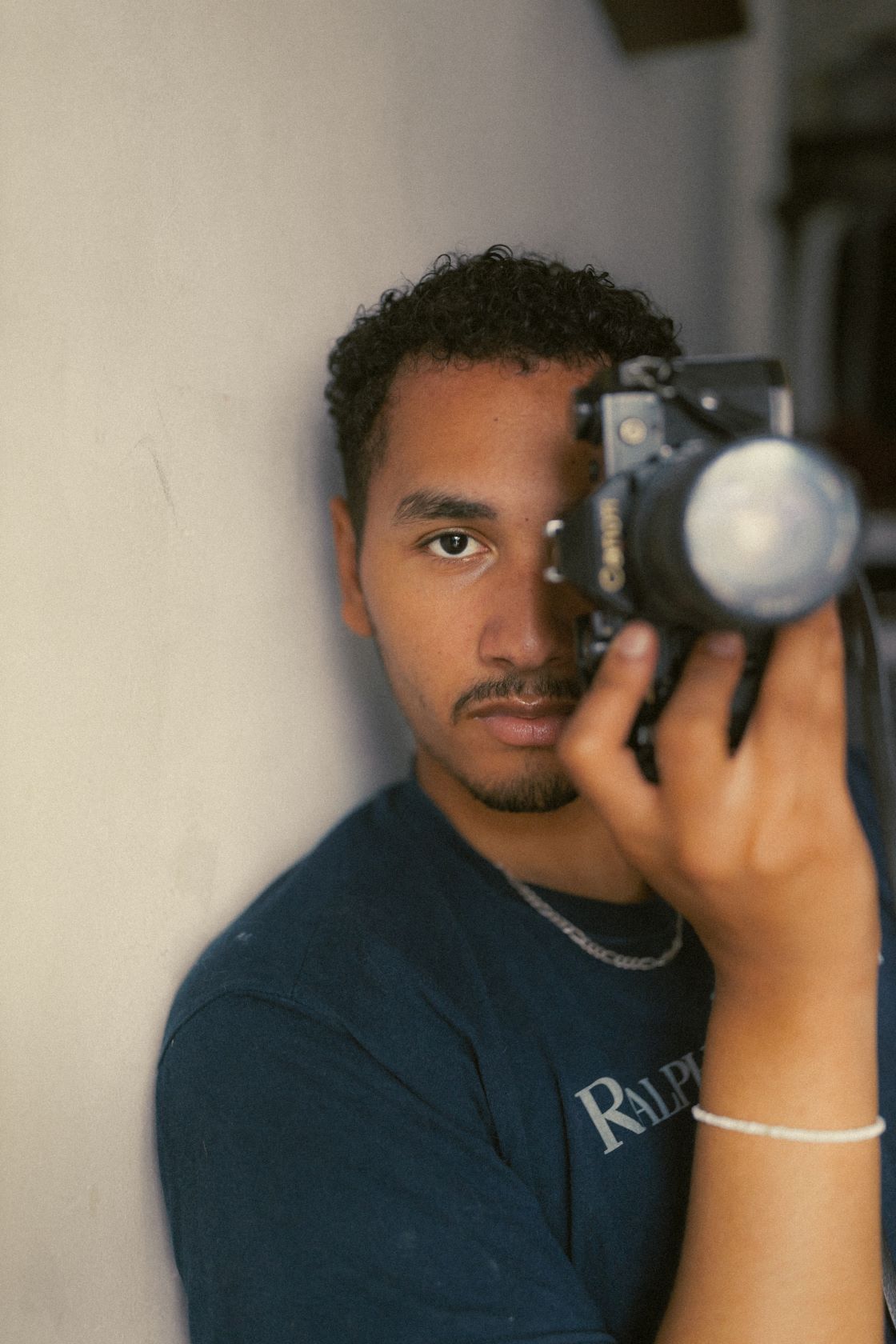 Kassim le photographe tenant une camera cachant un oeil