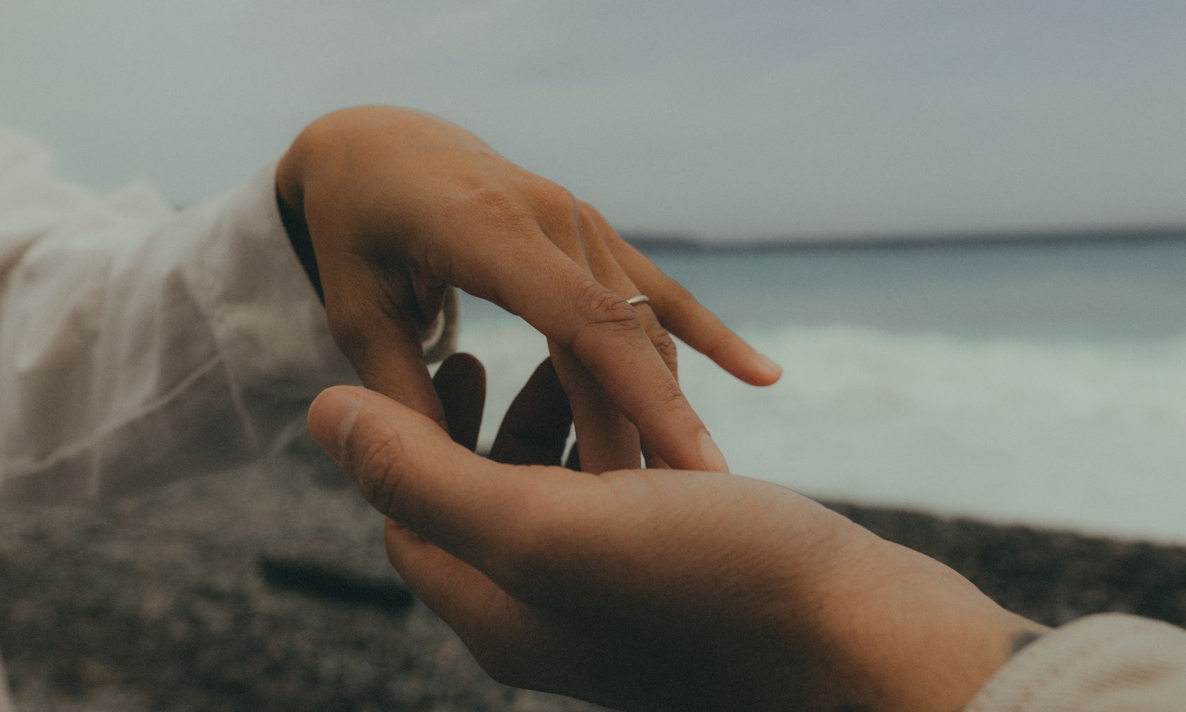 Deux mains qui se touchent face à la mer