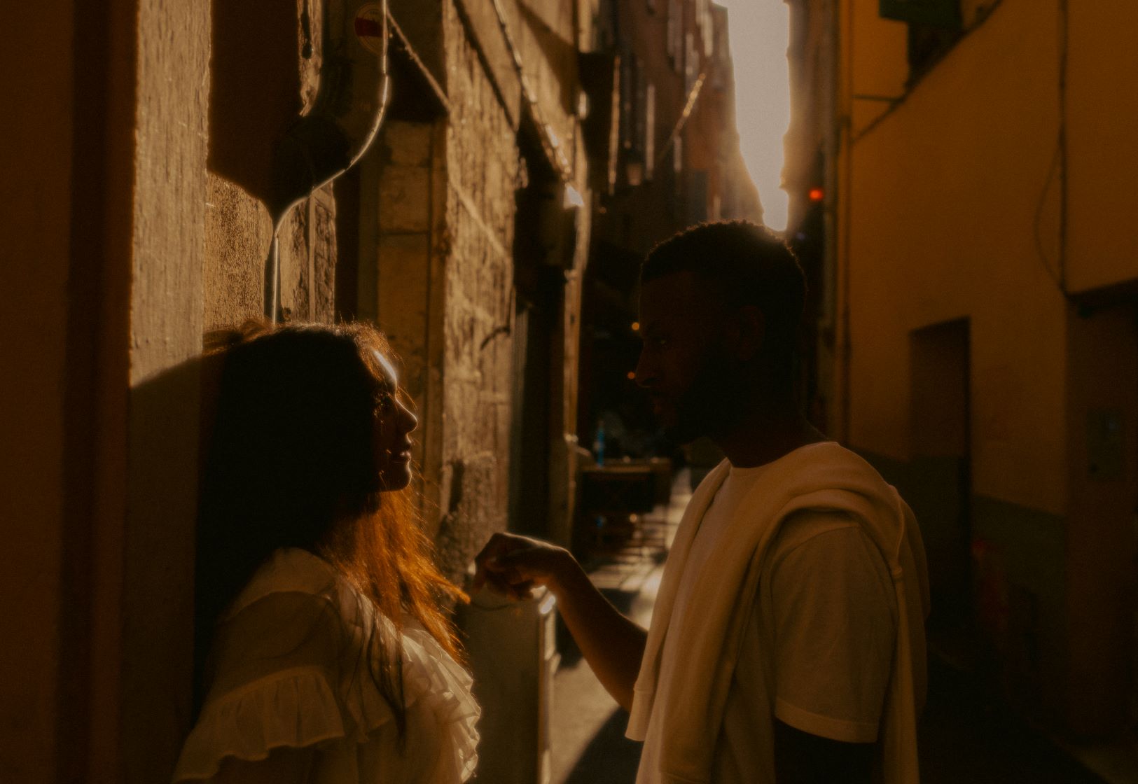 Couple dans une ruelle se regardant, la femme est contre un mur