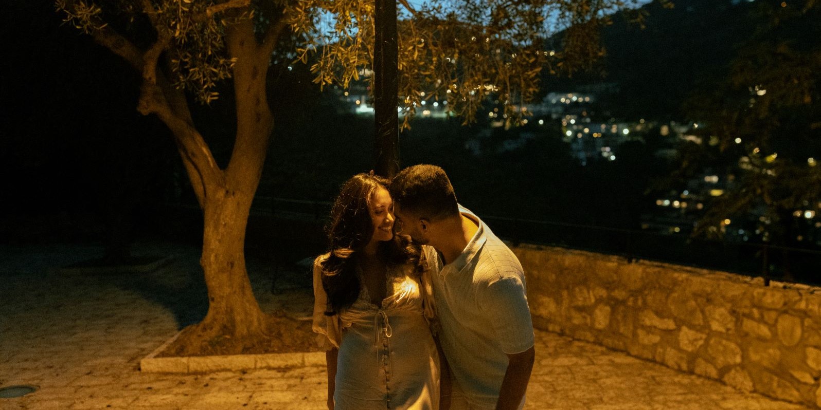 Couple souriant se regardant, éclairé par une lumière orange