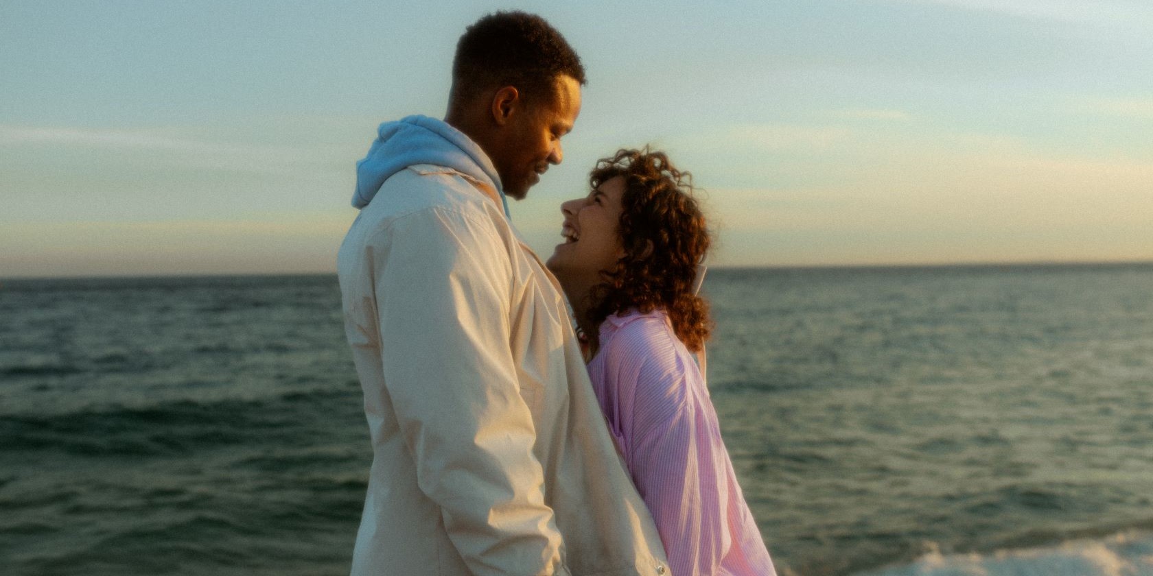 Couple souriant se regardant dans les yeux devant la mer