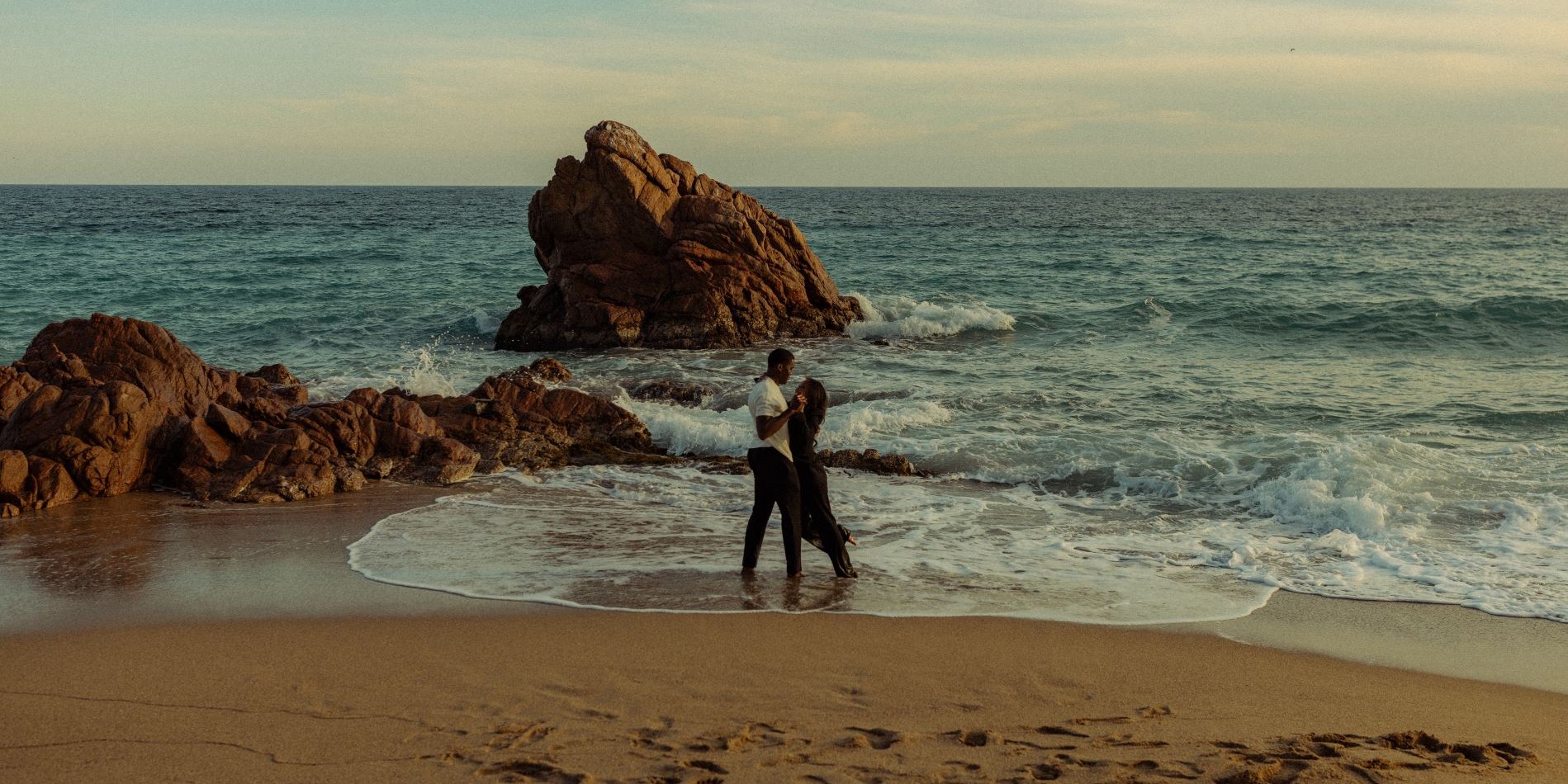 Couple face à face, se tenant les mains devant la mer