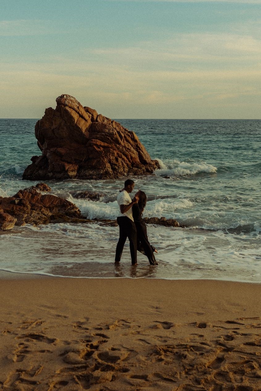 Couple face à face, se tenant les mains devant la mer
