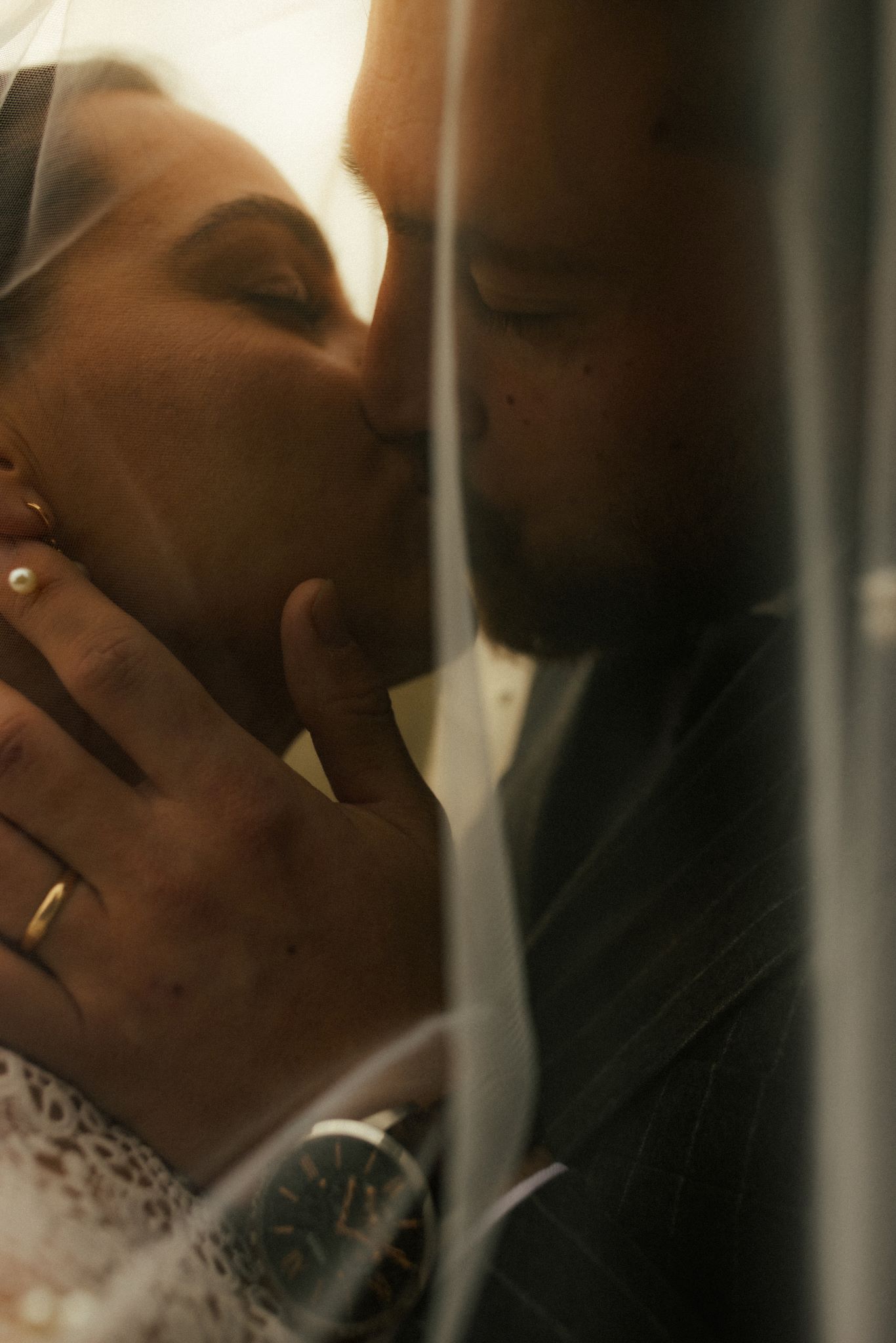 Couple sous le voile de la marié, s'embrassant